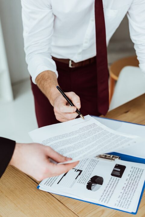 cropped view of businesspeople working with documents and signing contract